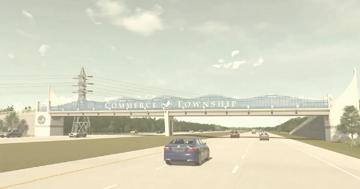 Commerce Township gateway bridge spanning a highway, with sail-shaped towers and a township emblem.
